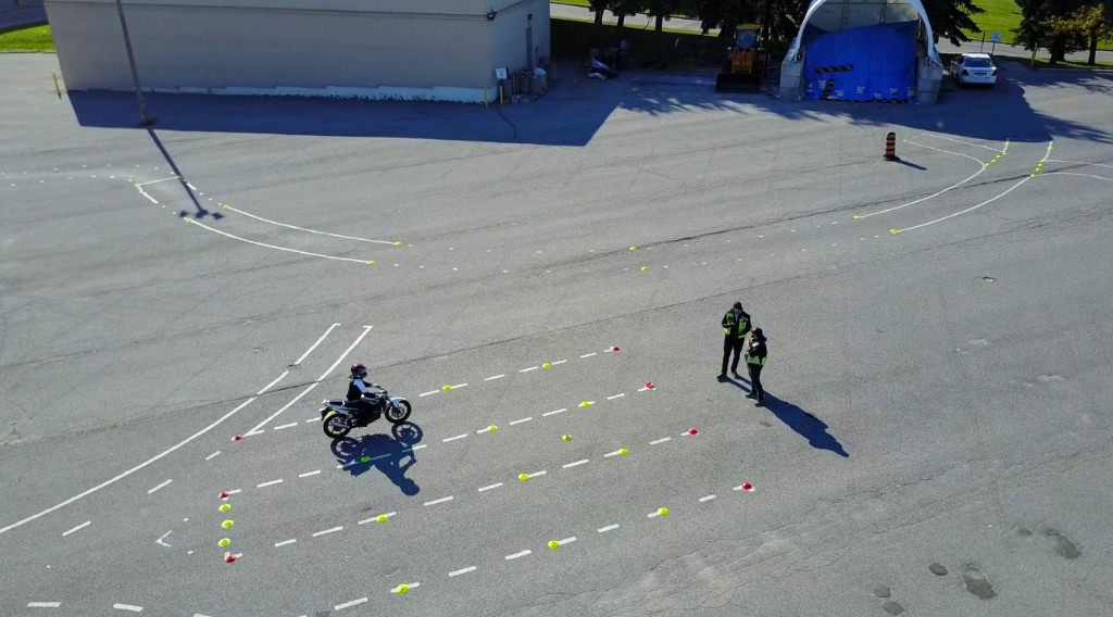 Drone view of a motorcycle training range with a student rider and two coaches