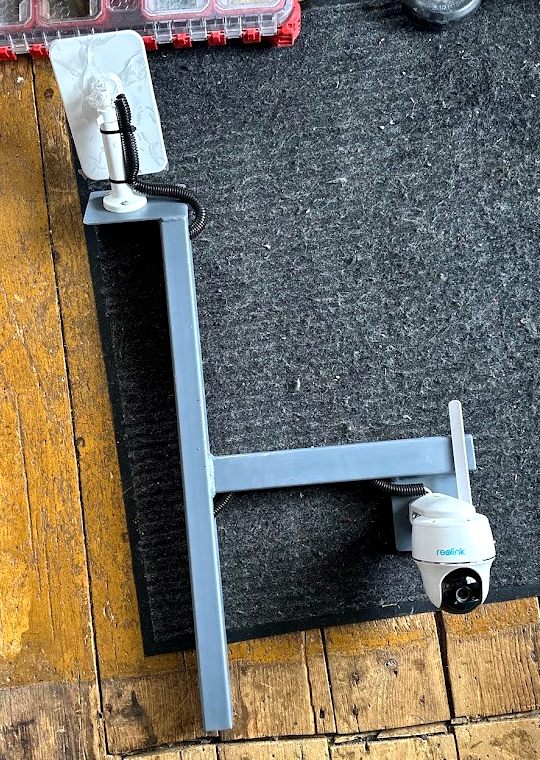 Custom fabricated steel mount holding a solar panel and Reolink camera