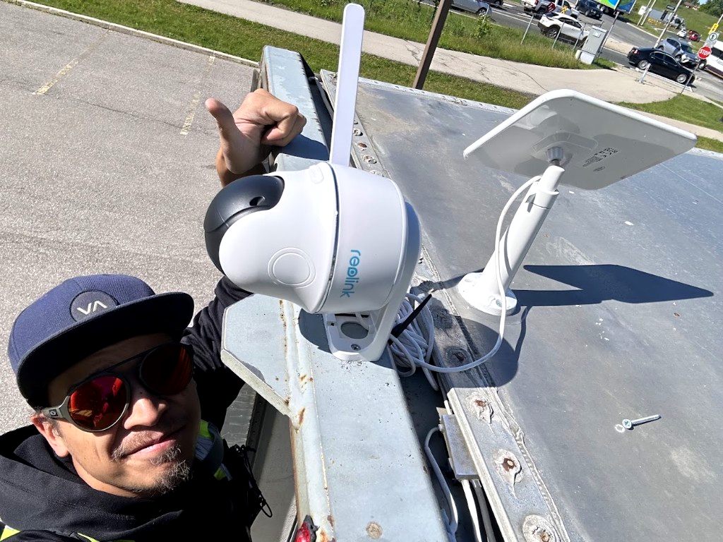 Alex installing a solar-powered Reolink camera on a container roof